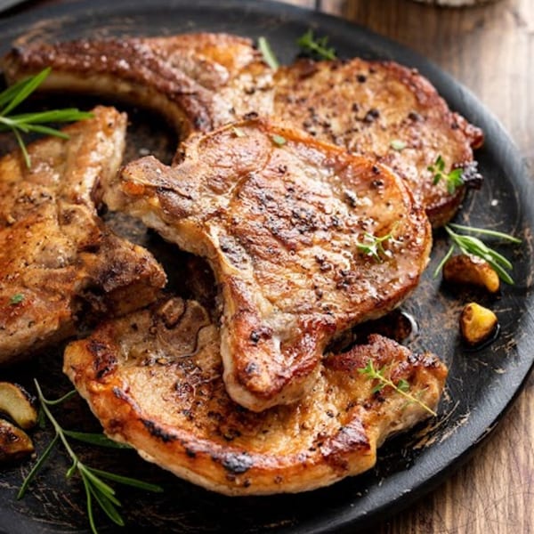 Grilled pork chops with rosemary and garlic on a dark plate at The Grill.